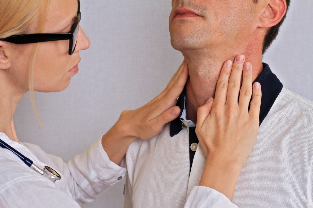 female doctor checking neck and thyroid area of man