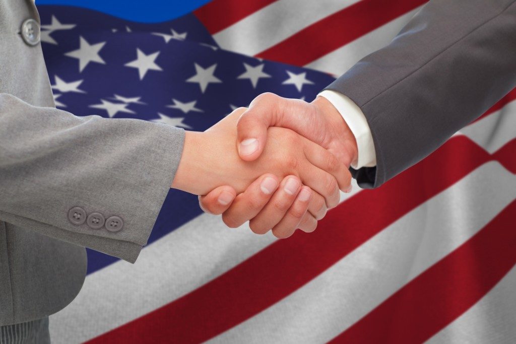 men shaking hands and the american flag