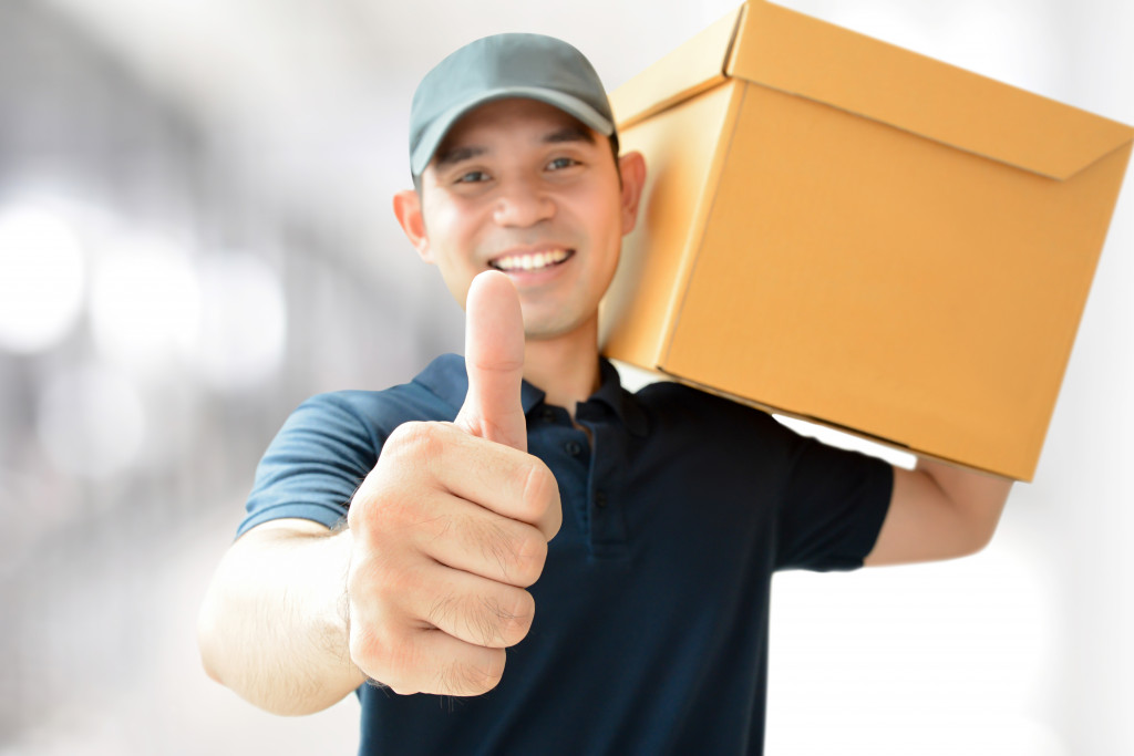 man giving a thumbs up while holding a box